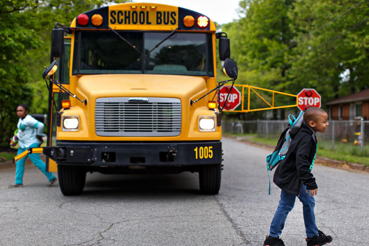 Children exiting a school bus with its stop-arm extended